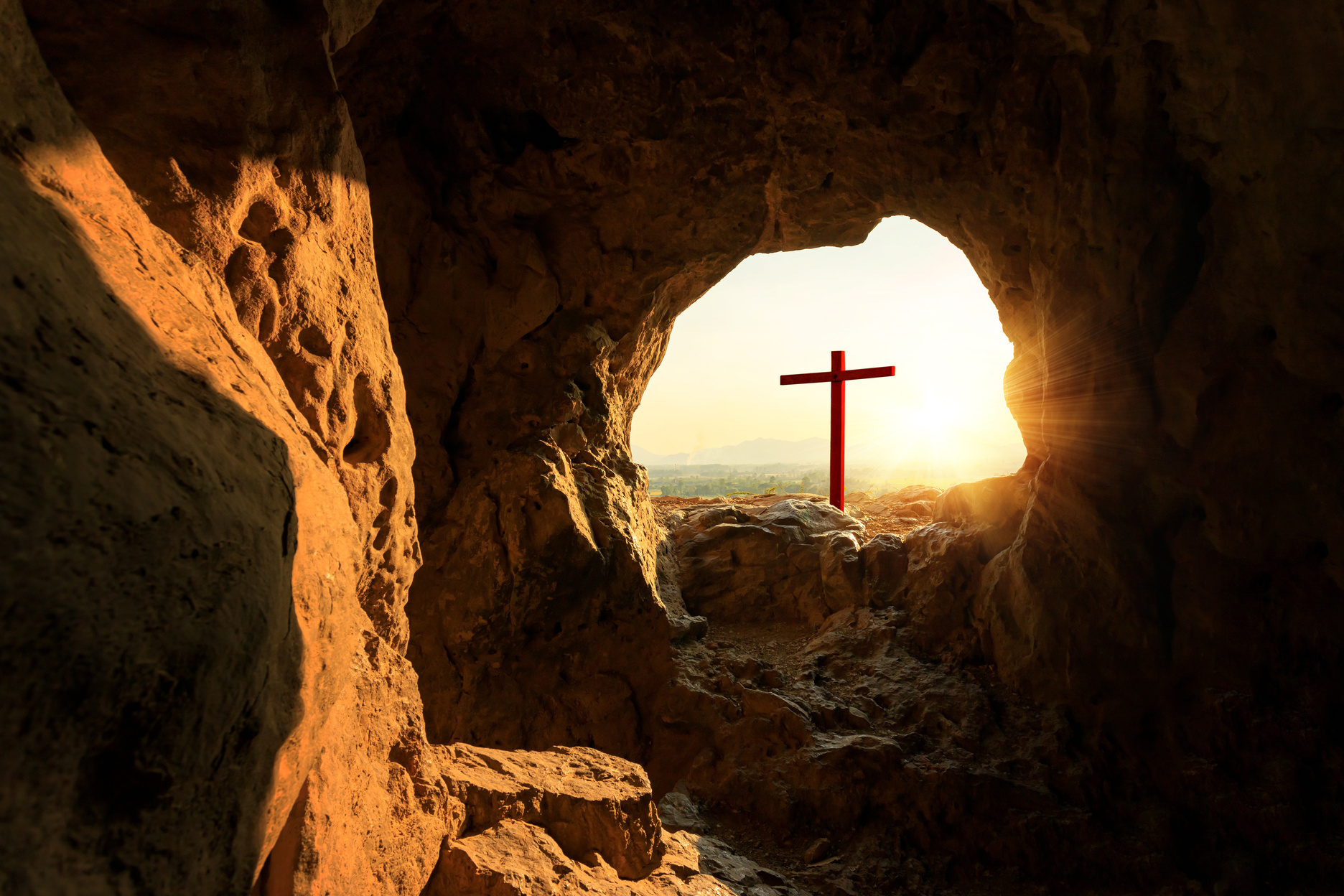 Empty cemetery with crucifixion at sunset from cave mouth